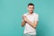 Portrait of smiling devious young man in casual clothes standing and rubbing palms isolated on blue turquoise wall