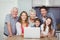 Portrait of smiling family with laptop in kitchen