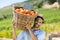 Portrait of smiling farmer carrying by fresh oranges in container