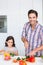 Portrait of smiling father cutting zucchini with daughter