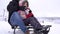 Portrait of smiling father and daughter sled on in a ski resort. Smiling family sitting on the sled. Winter vacation