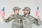 portrait of smiling father and son in camouflage clothing with american flagpoles in hands