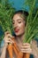 Portrait of smiling female fashion model hiding behind carrot leaves