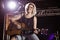 Portrait of smiling female guitarist playing guitar at nightclub