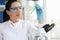 Portrait of smiling female scientist with glasses holding chemical test tube in laboratory