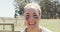 Portrait of smiling female soldier wearing eye black standing in field on obstacle course in sun