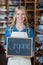 Portrait of smiling female staff holding a organic sign board