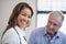 Portrait of smiling female therapist with senior male patient in background