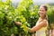 Portrait of smiling female vintner inspecting grape crop
