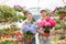 Portrait of smiling gardeners holding flower pots at greenhouse