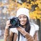 Portrait of smiling girl with bonnet and camera, autumn.