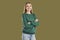 Portrait of smiling girl in green sweatshirt is posing on khaki background looking at camera.