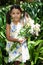 Portrait of smiling girl holding flowers bouquet standing amidst plants