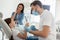 Portrait of smiling girl looking in the mirror after dental procedure while mother standing near her for support