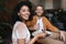 Portrait of smiling girl sitting in restaurant with friend. Nice African American lady sitting at cafe with plate of