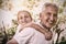 Portrait of smiling grandfather carrying granddaughter piggyback