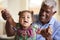 Portrait Of Smiling Grandfather Sitting On Sofa At Home With Baby Granddaughter