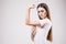 Portrait of a smiling happy girl flexing biceps with a measuring tape around her arm over gray background. Health concept