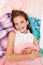 Portrait of smiling happy little girl child schoolgirl lying on her clothes choosing dresses
