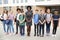 Portrait Of Smiling High School Student Group With Female Teacher Standing Outside School Buildings