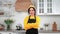 Portrait smiling housewife looking camera with crossed hands in home kitchen