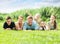 Portrait of smiling large family lying together on green lawn outdoors