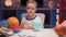 Portrait smiling little blond boy sitting at home at table near planet Uranus around many planets of solar system. Child