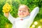 Portrait of a smiling little girl lying on green grass with a bunch of yellow dandelions. Cute five years old child enjoying natur