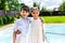 portrait of smiling little siblings hugging each other with swimming pool behind