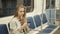 Portrait of a smiling lovely girl typing message on mobile phone in subway train, student blonde woman with