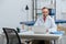 portrait of smiling male chiropractor in white coat at workplace with laptop