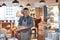 Portrait Of Smiling Male Owner Of Delicatessen Shop Wearing Apron Holding Loaf Of Bread