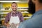 Portrait of smiling male staff holding a meat packet at counter