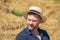 Portrait of a smiling man 35-40 years old with a beard in a straw hat on a field with hay. Concept: farming and agriculture, summe