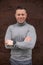 Portrait of smiling man in gray sweater, confident, stands against wall of city office building. Freelance.