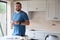 Portrait Of Smiling Man Renovating Kitchen At Home Looking At Paint Swatches On Coffee Break