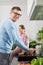 Portrait of smiling man washing hands with daughter sitting on counter in kitchen