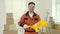 Portrait of the smiling man worker standing, holding paint roller and plastic tub in new apartment renovation room