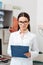 portrait of smiling optometrist in white coat with notepad in hands looking