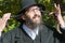Portrait of smiling orthodox Jewish man holding long Sidelocks, Peyot, Payot