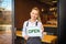 Portrait of smiling owner standing at restaurant door holding open sign, small family business