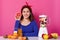 Portrait of smiling positive female holding cut fruit in her hand. Young model waits for smoothie to be ready. Cheerful happy