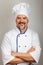 Portrait of a smiling professional chef cook man dressed a chef uniform, grey background