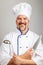 Portrait of a smiling professional chef cook man with a kitchen knife and a soup ladle, dressed a chef uniform, grey background
