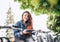 Portrait of smiling red curled long hair caucasian teen girl block out bike at Bicycle sharing point using the modern smartphone.