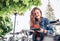 Portrait of smiling red curled long hair caucasian teen girl block out bike at Bicycle sharing point using the modern smartphone.