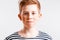 Portrait of a smiling red-haired boy with freckles and braces in a sailor suit on a white background,