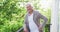 Portrait of smiling retired senior man wearing cardigan sweater leaning on railing in balcony