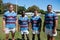 Portrait of smiling rugby team standing on grassy field