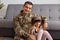 Portrait of smiling satisfied young adult soldier man wearing camouflage uniform returning home after army, spending time with